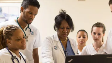 Student nurses gather around a computer