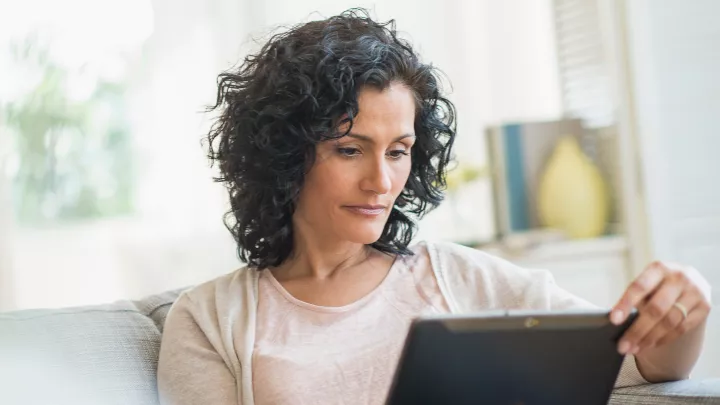 Woman using a tablet on sofa to schedule a consultation 