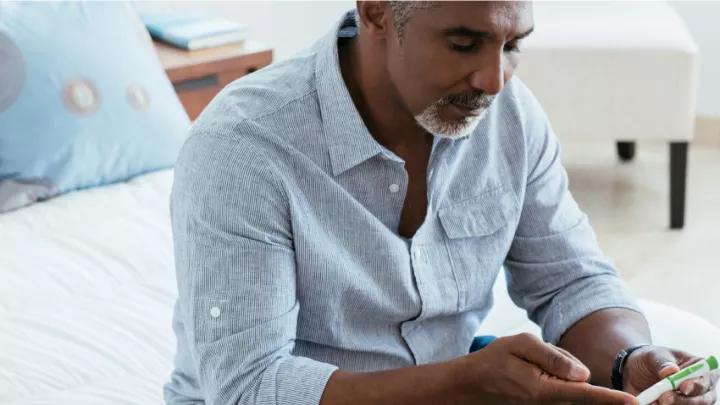 Middle aged man using a diabetic lancet to test blood sugar
