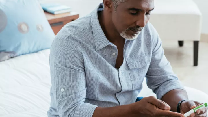 Middle aged man using a diabetic lancet to test blood sugar