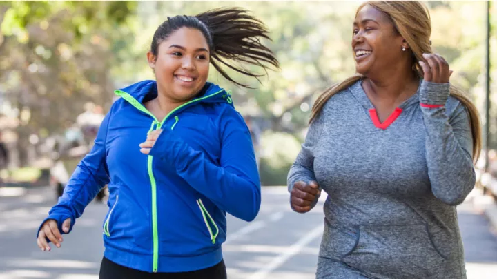Two women in sweatshirts smiling and jogging together