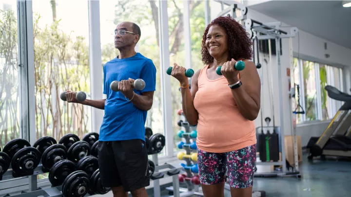 Man and woman using dumbbells to exercise together at the gym