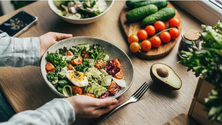 Bowl of salad on table featuring a variety of healthy fats such as avocado 