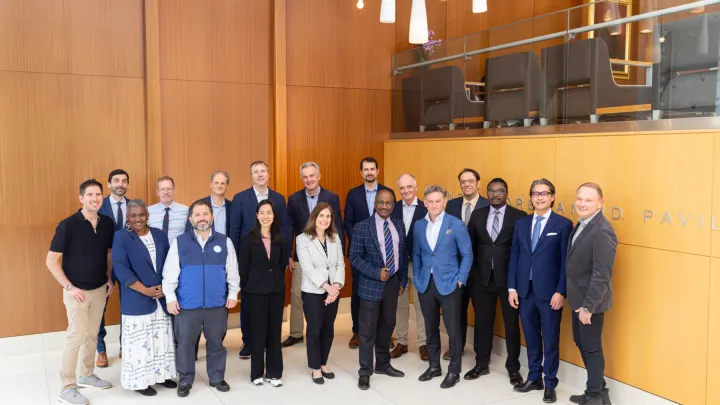 Group of professionally dressed individuals posing for a photo in a modern building lobby with wood-paneled walls and signage
