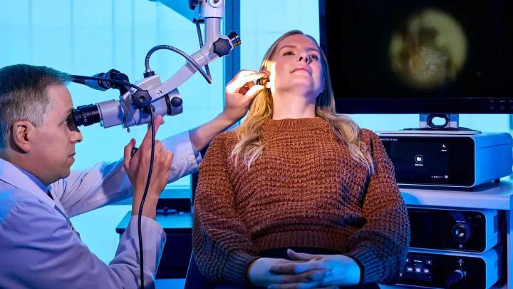 Doctor in white coat using ultrasound device on a patient's neck.