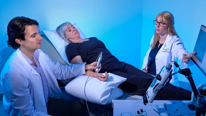 Medical team conducting a diagnostic procedure on a patient’s hand using ultrasound and nerve monitoring equipment.