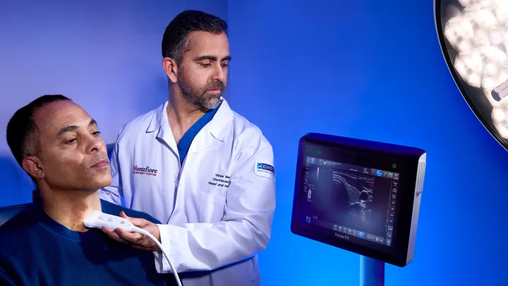 Doctor in white coat using ultrasound device on a patient's neck.