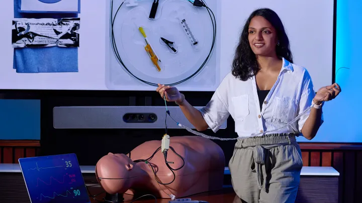 Medical student presents a central line kit and simulation mannequin during an emergency medicine training session.