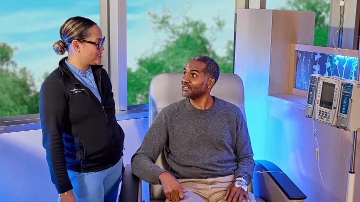 "Patient receiving IV treatment in a bright, modern infusion center while speaking with a Montefiore Einstein oncology nurse.