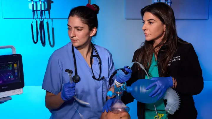Two advanced practice nurses provide emergency respiratory care, monitoring a patient on a ventilator.