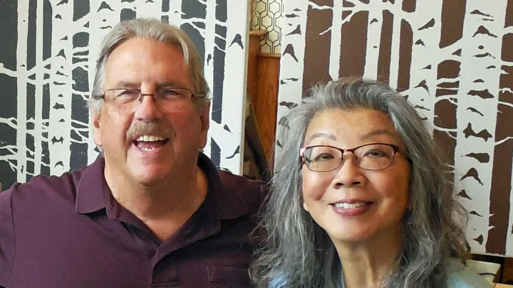 Connie & Steve Delehanty seated together in front of a patterned background
