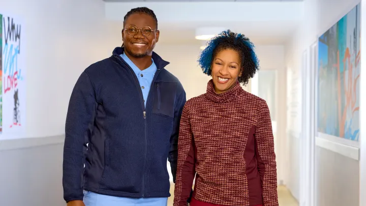 A man and a woman smiling and standing in a hallway