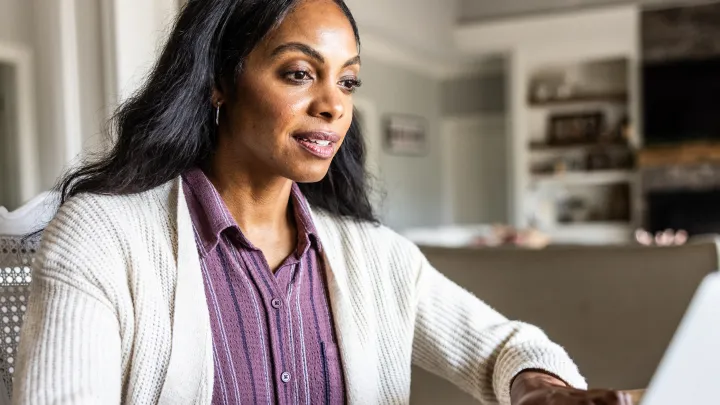 Woman sitting at a table with her hands on a laptop keyboard