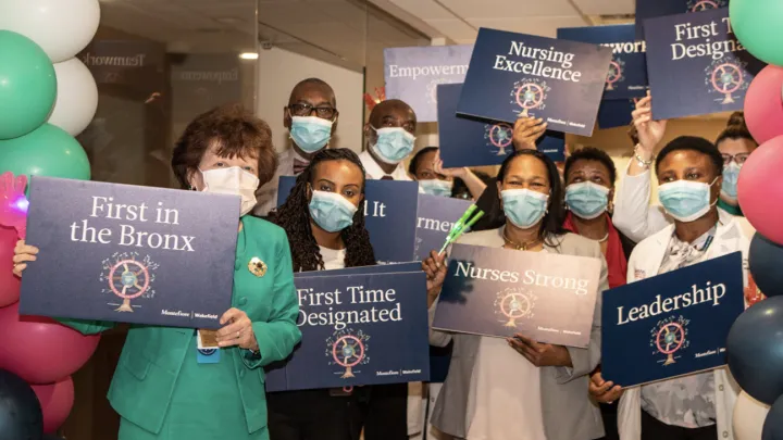 Group of health care workers holding signs as they stand next to balloons