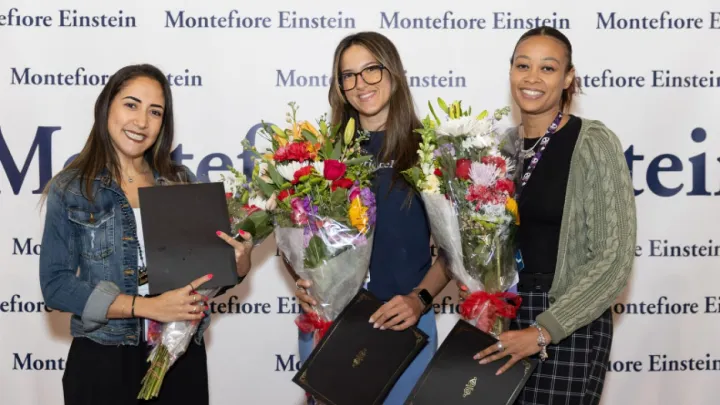 Three women nurses holding flowers and their awards smiling.
