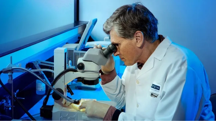 A physician looks at a slide using a microscope.