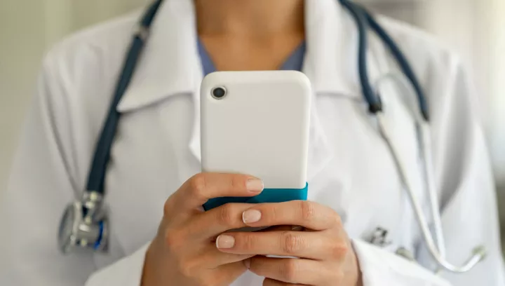 A doctor referring a patient by texting on a smartphone