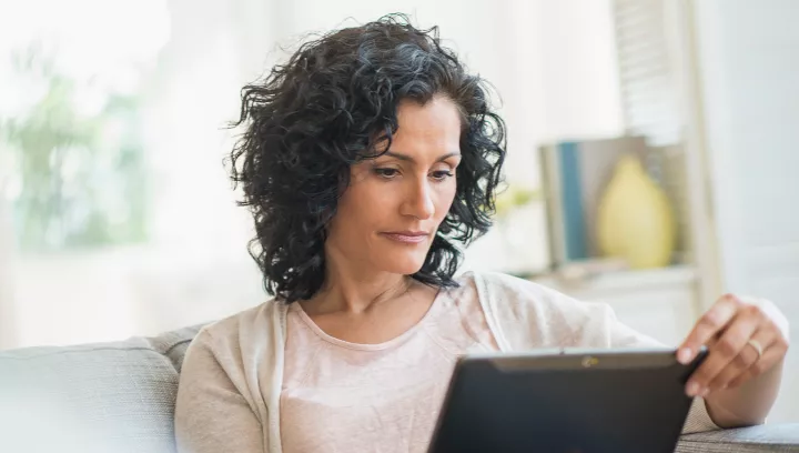 Woman using a tablet on sofa to schedule a consultation 