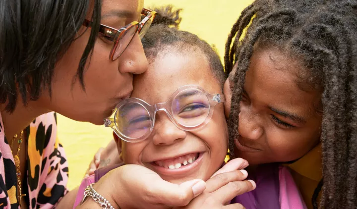 Close up of boy being kissed by mother and brother.