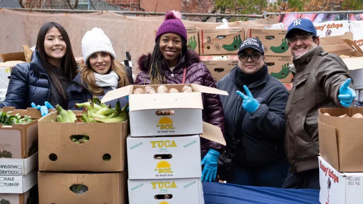 Volunteers in winter coats smiling next to fresh produce