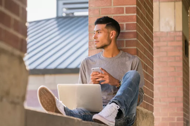 Young man seated with laptop and smartphone