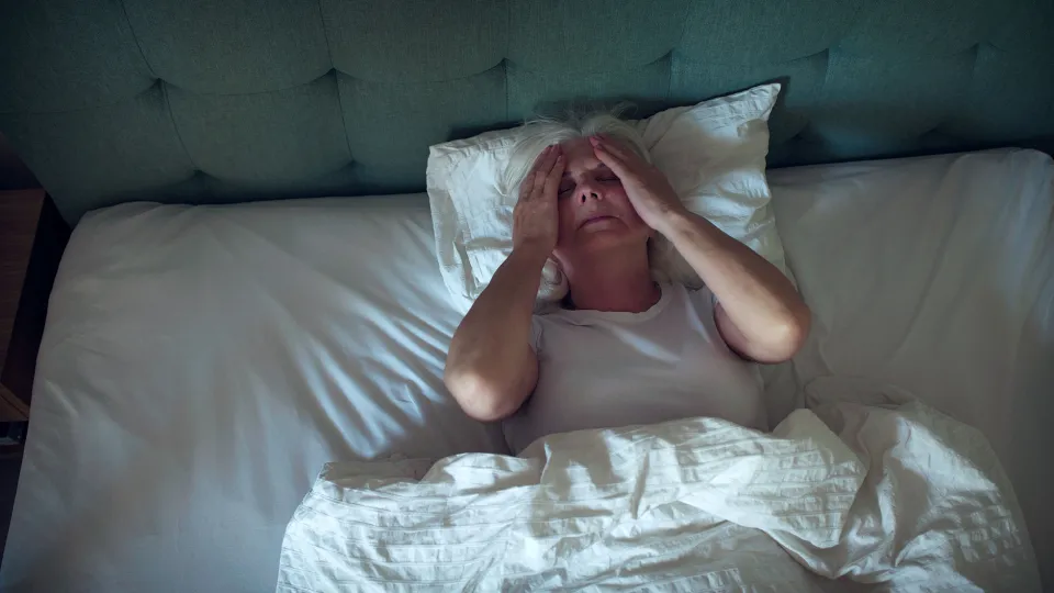 Anxious, mature woman trying to sleep at night. Dealing with sleeping disorder, head in hands