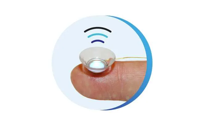 A TECLens device balanced on a fingertip. Curved lines emanate from the lens indicating wireless functionality.