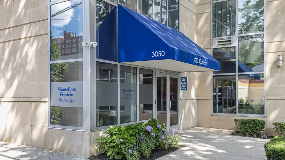 Entrance to Montefiore Einstein Radiology at 3050 Corlear Avenue in the Bronx, featuring a blue awning over glass doors and frosted windows.